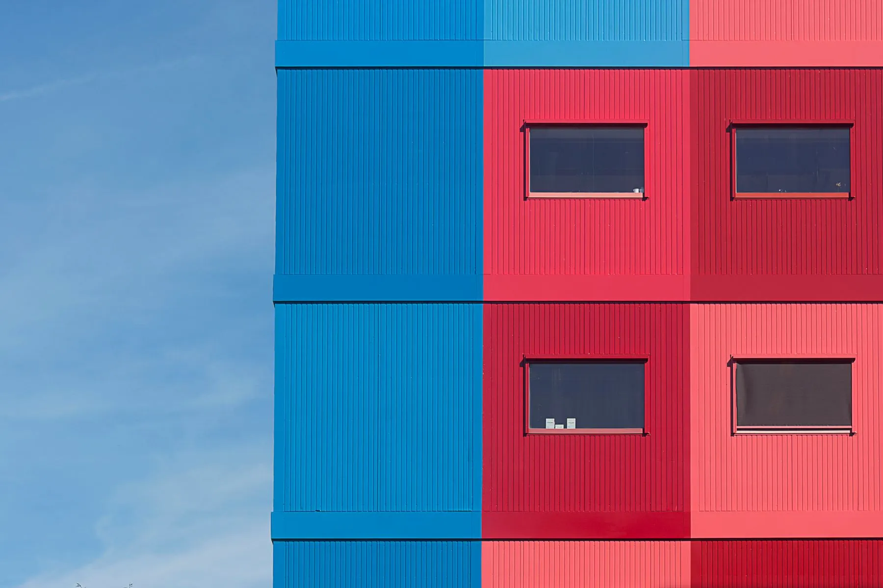 Geometric blue and vermilion building facade against a clear sky