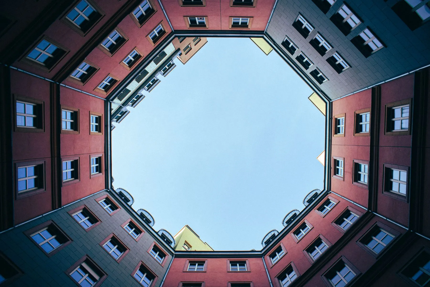 Symmetrical red and blue buildings framing open sky